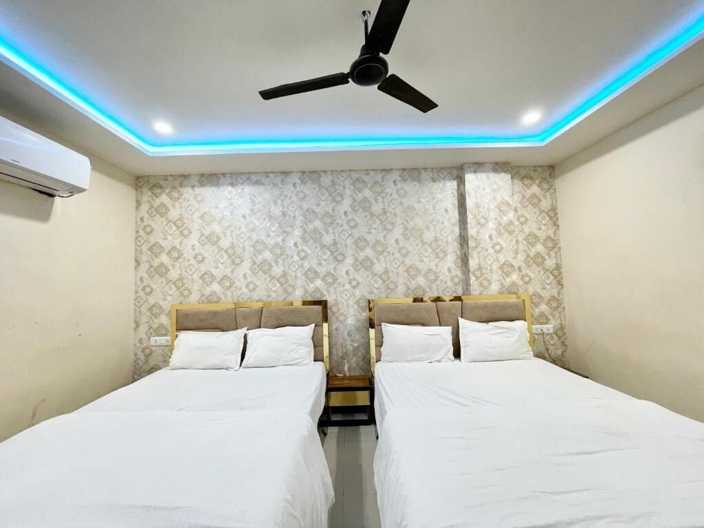 A hotel room with two beds, a ceiling fan, and patterned wallpaper.