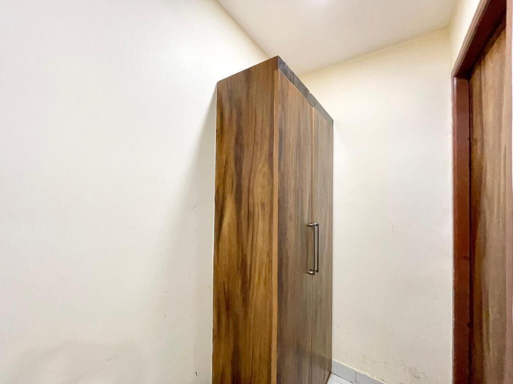 Un armario alto y estrecho con acabado de madera y un solo tirador.