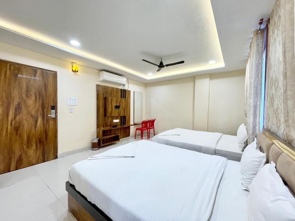 A hotel room with two beds, a ceiling fan, a desk, and a red chair.