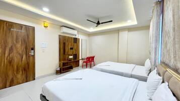 A hotel room with two beds, a ceiling fan, a desk, and a red chair.