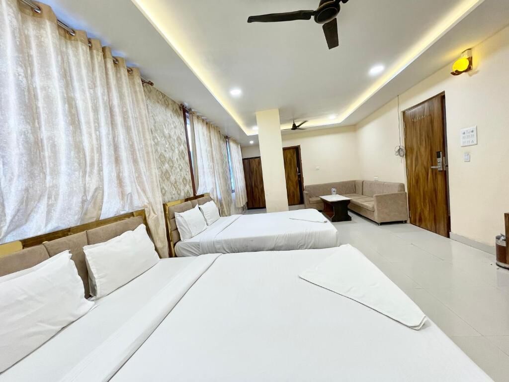 A hotel room with two beds, a sofa, a ceiling fan, and a door with a sign.