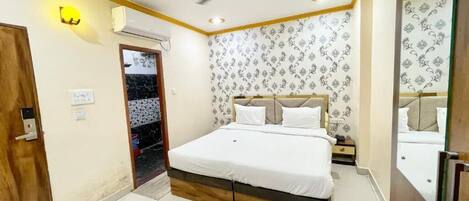 A bedroom with a bed, a ceiling fan, a mirror, and a door.