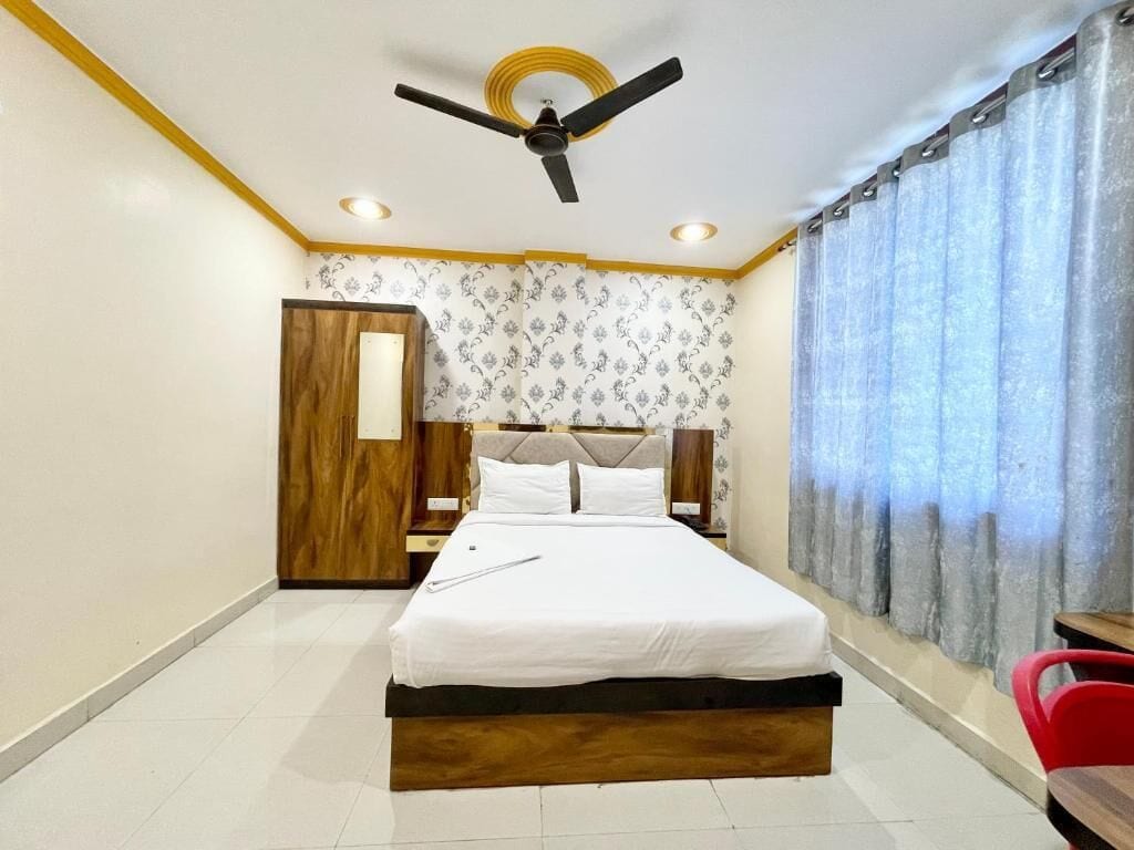 Ein Hotelzimmer mit Bett, Holzschrank, Deckenventilator und einem fenster mit Vorhängen.