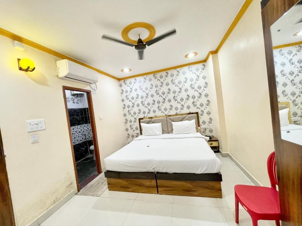 Un dormitorio con una cama, ventilador de techo, aire acondicionado y una silla roja.