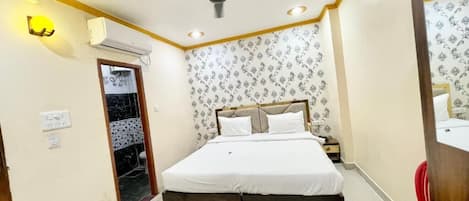 Une chambre à coucher avec un lit, un ventilateur de plafond, un climatiseur et un fauteuil rouge.