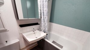 Ein Badezimmer mit einem weißen Waschbecken, einer Toilette, einer Badewanne und einer Duschvorhang.