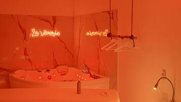 A room with a marble wall, a bathtub, a mirror, and a neon sign.