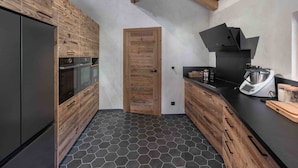 A modern kitchen with wooden cabinetry, a black countertop, and a hexagonal tile floor.