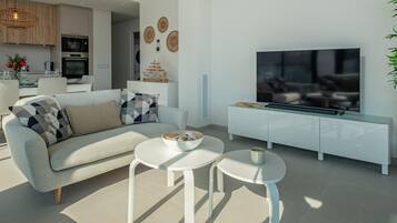 Una sala de estar moderna con un sofá, dos mesas auxiliares blancas, un televisor de pantalla plana y una cocina minimalista al fondo.