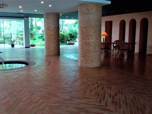 A spacious indoor area with brick flooring, large pillars, and a seating area with tables and chairs. - Bright Apartment, by the Natural Park, Pool, Wi-Fi, Near Dog-Friendly Beach, Terrace & Bike Storage (Roses)
