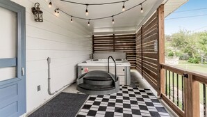 A covered outdoor area with a checkered floor, a hot tub, and string lights.