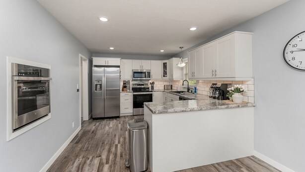 A modern kitchen with stainless steel appliances, white cabinetry, and a central island.