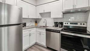 A modern kitchen with white cabinets, stainless steel appliances, and a granite countertop. - Barcelo at East Cobb Q5 1 Bd 1Bth Newly furnished (Marietta)