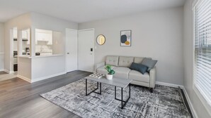 Un salon moderne avec un canapé, une table basse et une vue sur la cuisine.