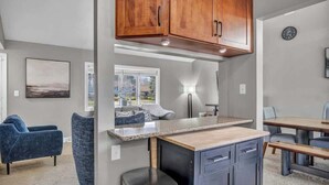 A modern kitchen with wooden cabinets, a countertop, and a dining area with a table and chairs. - Fenced backyard - Pets OK - 3 Bd 3 Ba (Mayfield Heights)