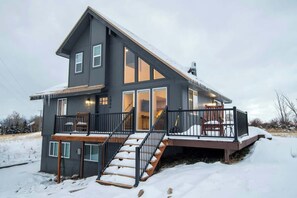 A modern two-story house with a balcony, large windows, and a staircase leading to the entrance. - Teton Homestead: Rocking Chair Ski Retreat (Driggs)