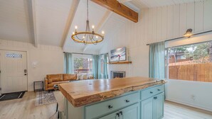 A kitchen with a wooden island, light blue cabinets, and a chandelier. - Chic Cabin Retreat with Hot Tub Big Bear (Big Bear Lake)