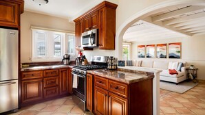 A kitchen with wooden cabinets, a stainless steel refrigerator, a microwave, and a stove.