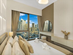A hotel room with a large bed, a bedside table with a lamp, a mirror, and a view of a cityscape.