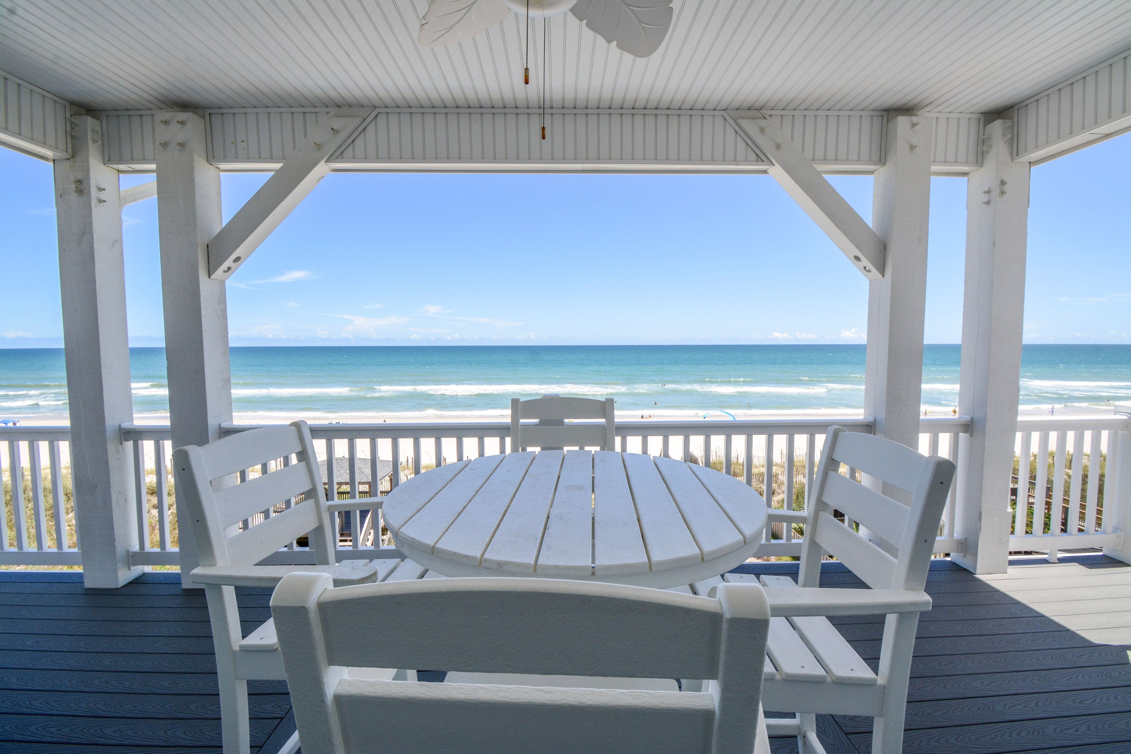 A covered outdoor seating area with a view of the ocean.