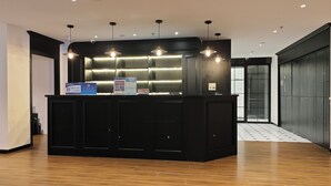 A reception desk with a black counter, overhead lighting, and informational posters. - Jianzhi Erqi Youth Hostel Xihu Branch (Hangzhou)