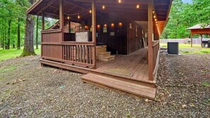 A wooden cabin with a porch, surrounded by trees. - Bear Moon - Broken Bow/Hochatown - 2b (Broken Bow)