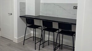A kitchen with a white countertop, three black bar stools, and a white cabinet. - Enchanting 4-bed House in Enfield (Enfield)