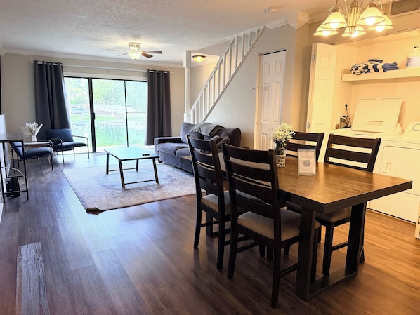 Una sala de estar moderna con comedor, escalera y cuarto de lavado.
