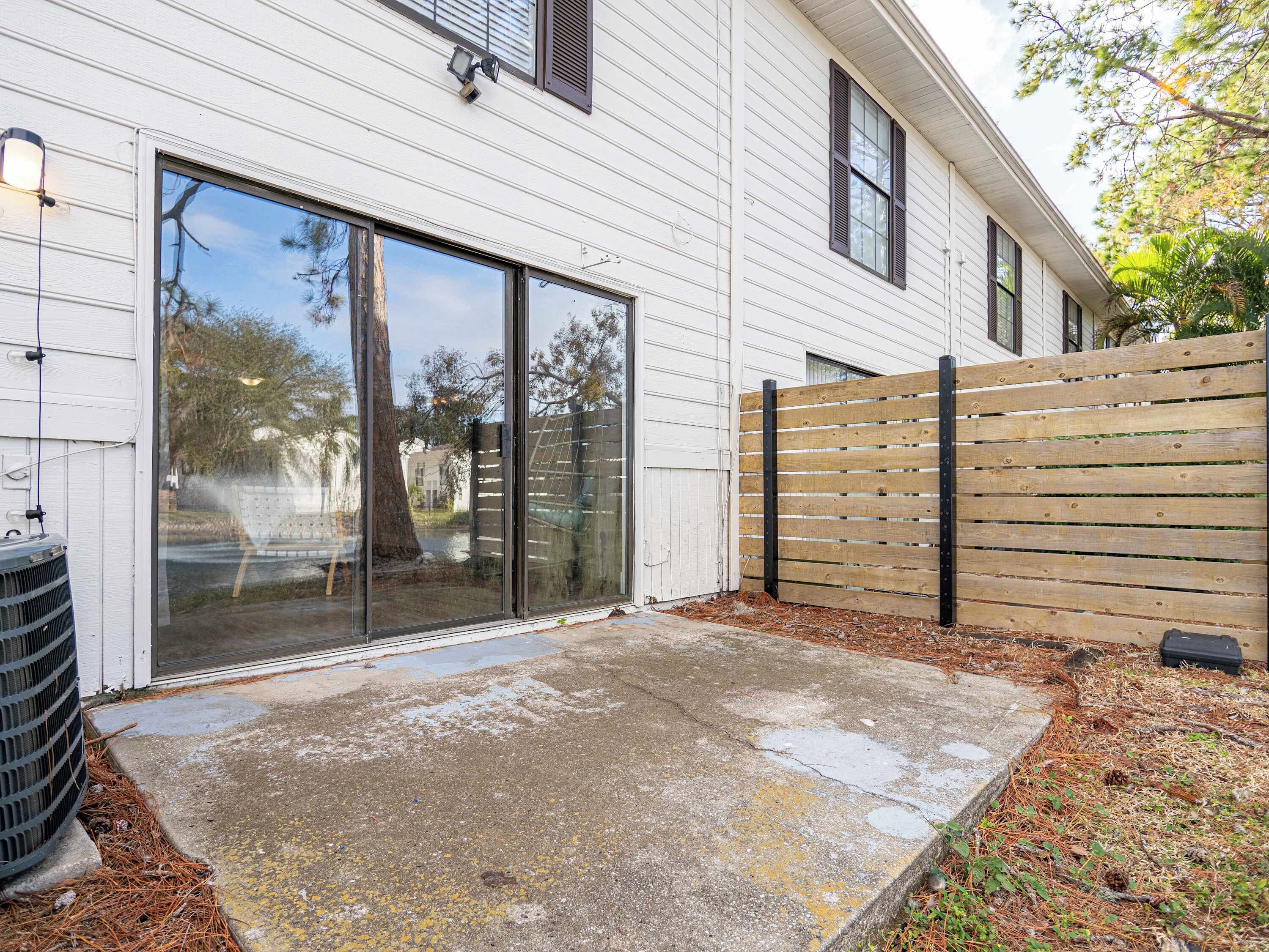 A house with a sliding glass door, a concrete patio, and a wooden fence.