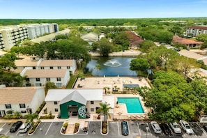 Vista aérea de un hotel con piscina, zona de estacionamiento y un río al fondo.