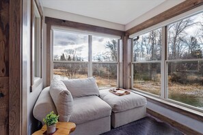A cozy room with a large window, a cushioned seating area, and a small table with a tray.
