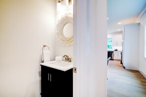 Bathroom features a vanity with a unique mirror and towel storage.