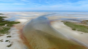 A coastal landscape with a wide sandy beach and a clear view of the sea.