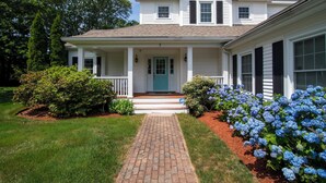 Una casa a due piani con un portico, una porta blu e un vialetto in mattoni che conduce all'ingresso.