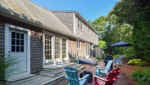 A house with a covered patio, outdoor seating, and a fire pit. - Walk to Beach, Private Patio and Backyard! (Chatham)