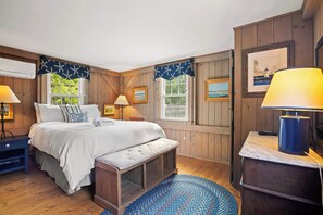 A cozy bedroom with a bed, bedside tables, a bench, and a rug.