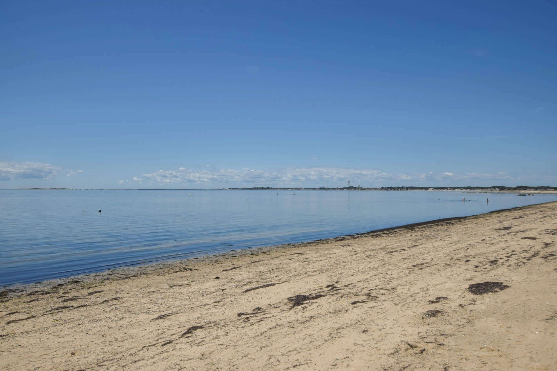 Una extensa playa de arena con aguas tranquilas que se extienden hasta el horizonte.
