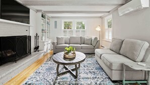 A living room with a fireplace, two sofas, a coffee table, and a bookshelf. - 3 Min to Mayflower Beach, Dog Friendly! (Dennis)