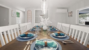 A dining room with a long table set for four, white railings, and a hanging light fixture. - 3 Min to Mayflower Beach, Dog Friendly! (Dennis)
