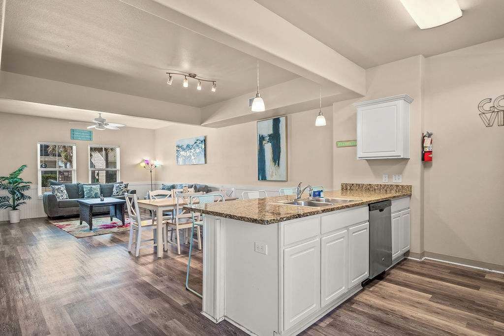 Una cocina amplia con una isla central, armarios blancos e iluminación colgante.