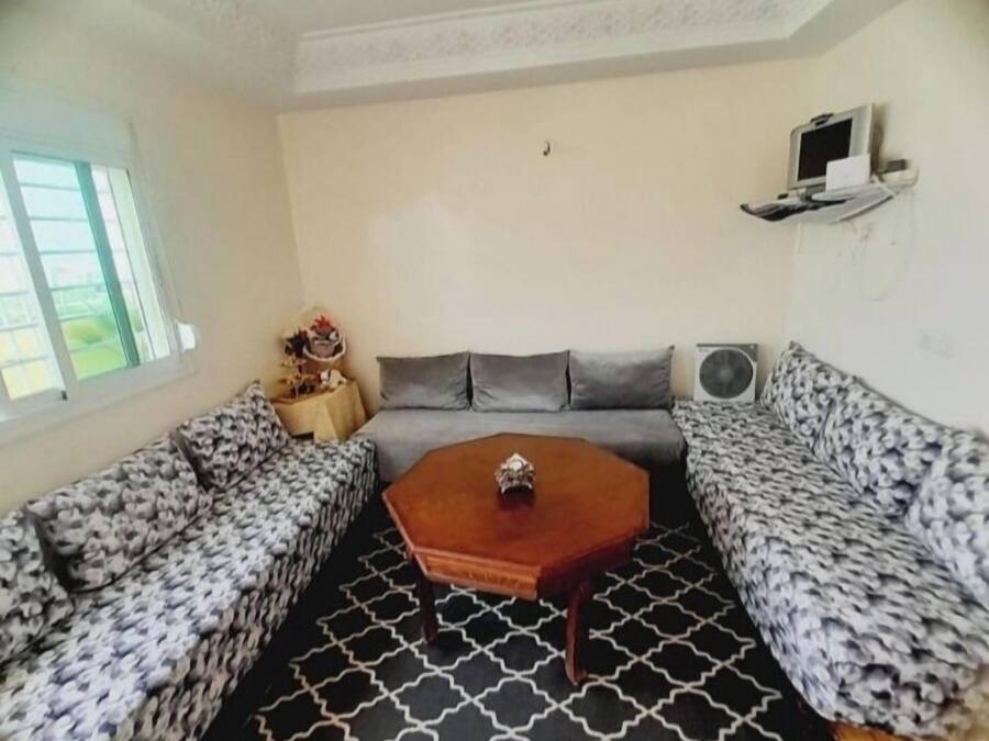 Una habitación con un sofá tapizado, una mesa de centro y un televisor sobre un mueble.