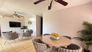 Un comedor moderno con una mesa redonda, seis sillas tapizadas y un ventilador de techo.