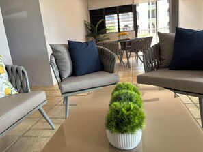A modern lounge area with sofas and chairs, a coffee table, and a potted plant.
