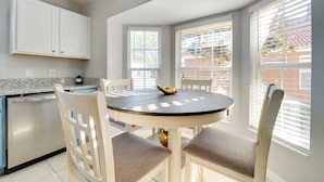 A kitchen with white cabinets, a dishwasher, and a round dining table with four chairs. - 11 Mi to Disney: Pet-friendly Aviana Resort Home! (Davenport)