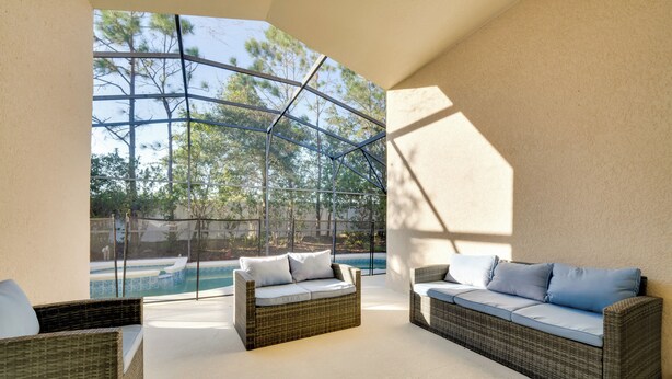 A sunlit outdoor seating area with wicker furniture and a view of a swimming pool. - 11 Mi to Disney: Pet-friendly Aviana Resort Home! (Davenport)