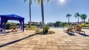 A poolside area with lounge chairs, a blue gazebo, and palm trees. - 11 Mi to Disney: Pet-friendly Aviana Resort Home! (Davenport)