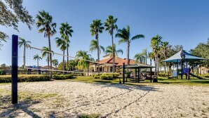 A beach volleyball court with palm trees, a gazebo, and a playground in the background. - 11 Mi to Disney: Pet-friendly Aviana Resort Home! (Davenport)