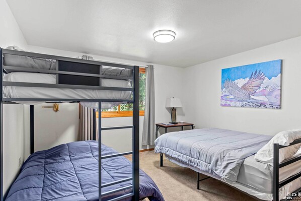 A room with bunk beds, a bedside table with a lamp, and a painting on the wall. - On-site Kenai River Fishing: Soldotna Apartment! (Soldotna)
