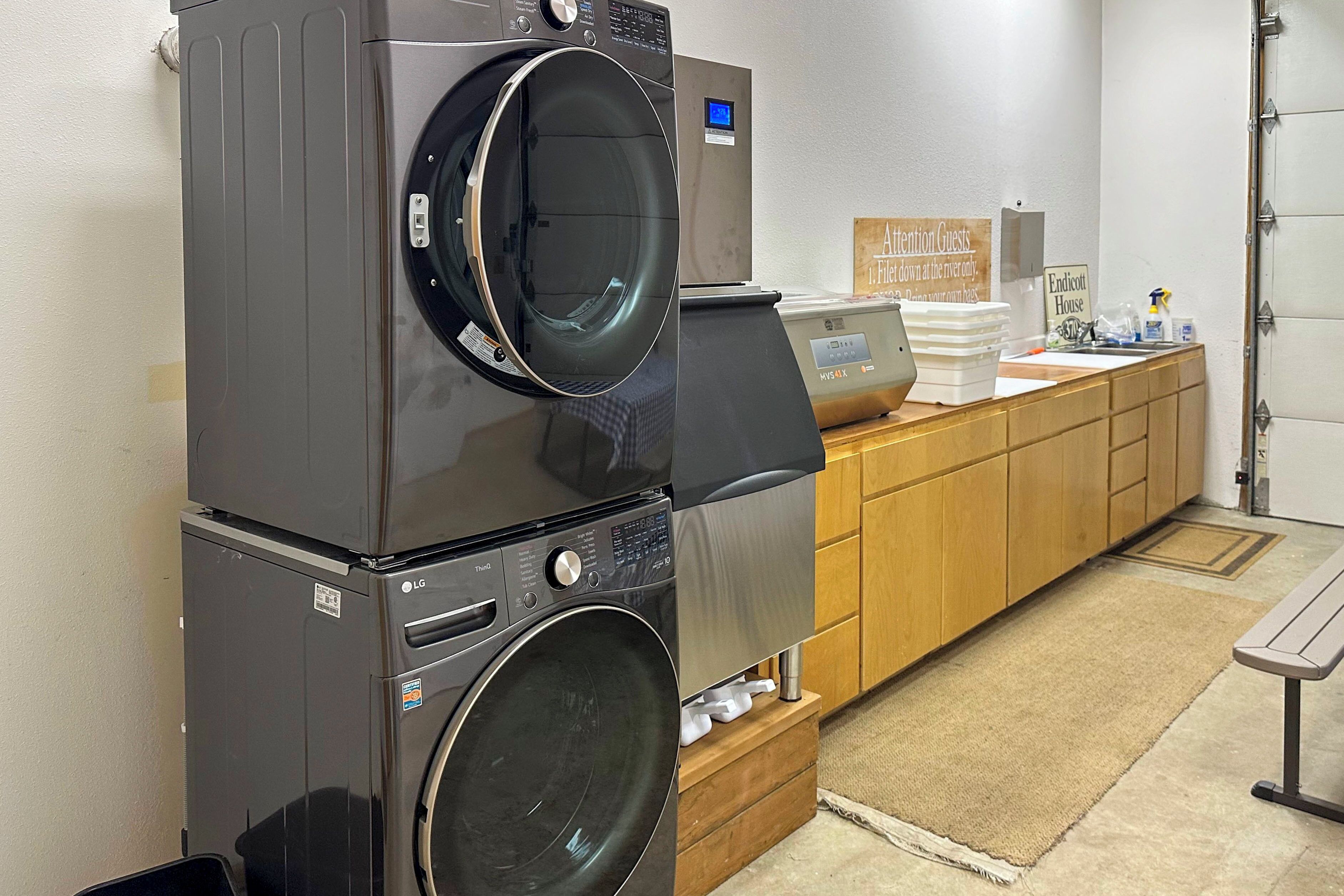A laundry area with stacked washers and dryers, a wooden counter with a sign, and a bench.