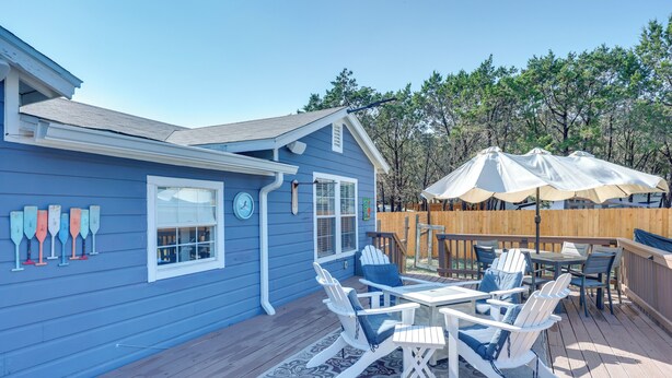 Una casa azul con terraza, muebles de exterior y valla de madera.